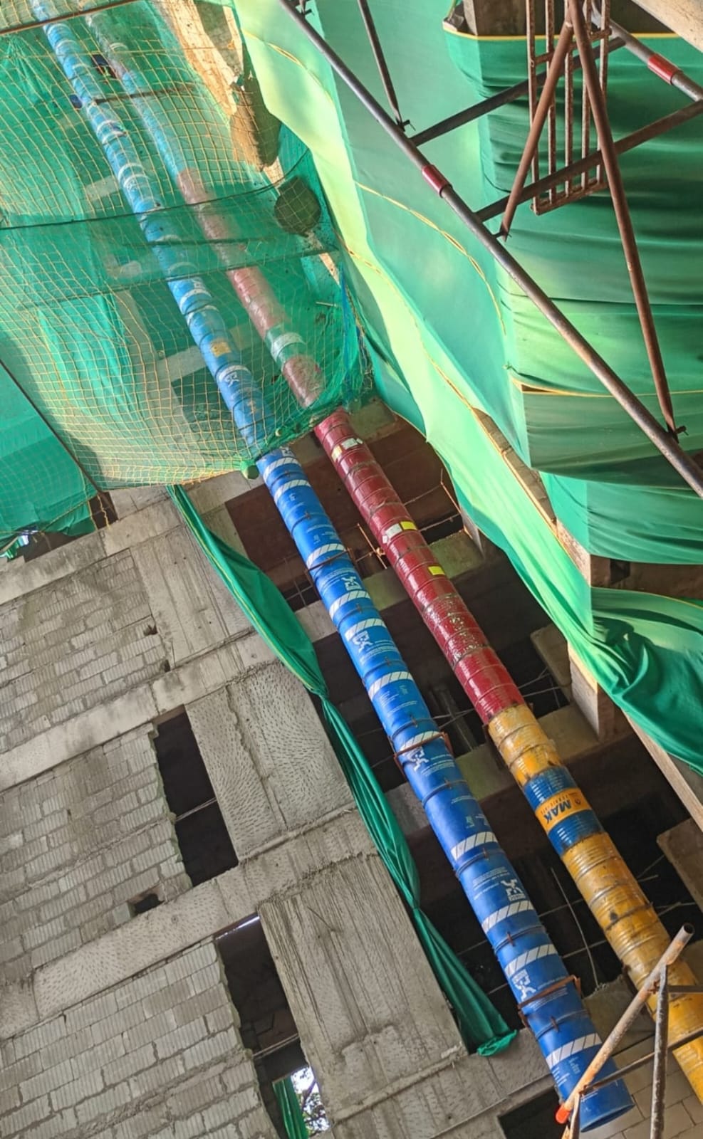 Blue and red debris chute sections installed through a multi-level construction site in Pune